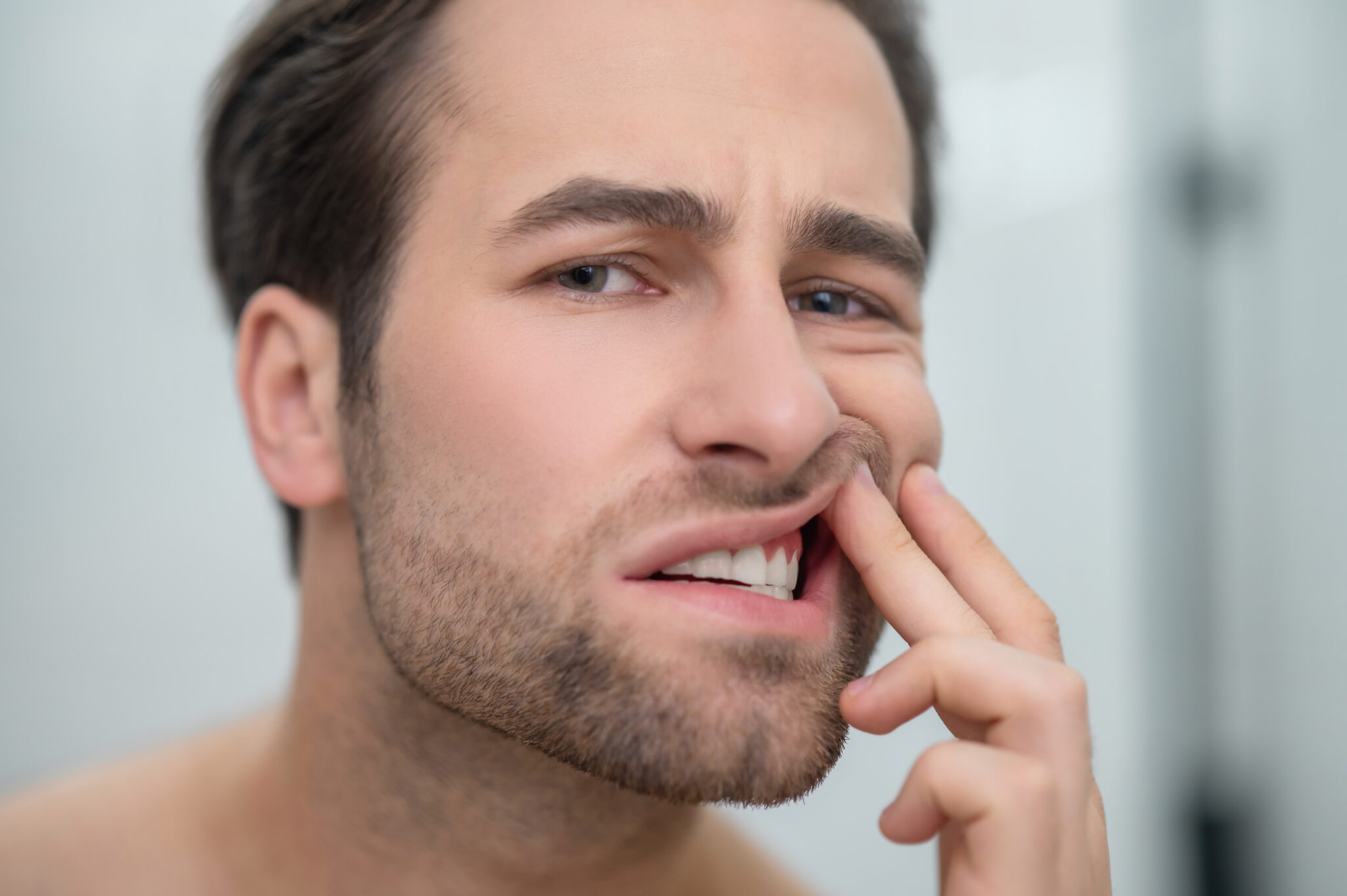 uomo che mostra denti doloranti e gengive arrossate